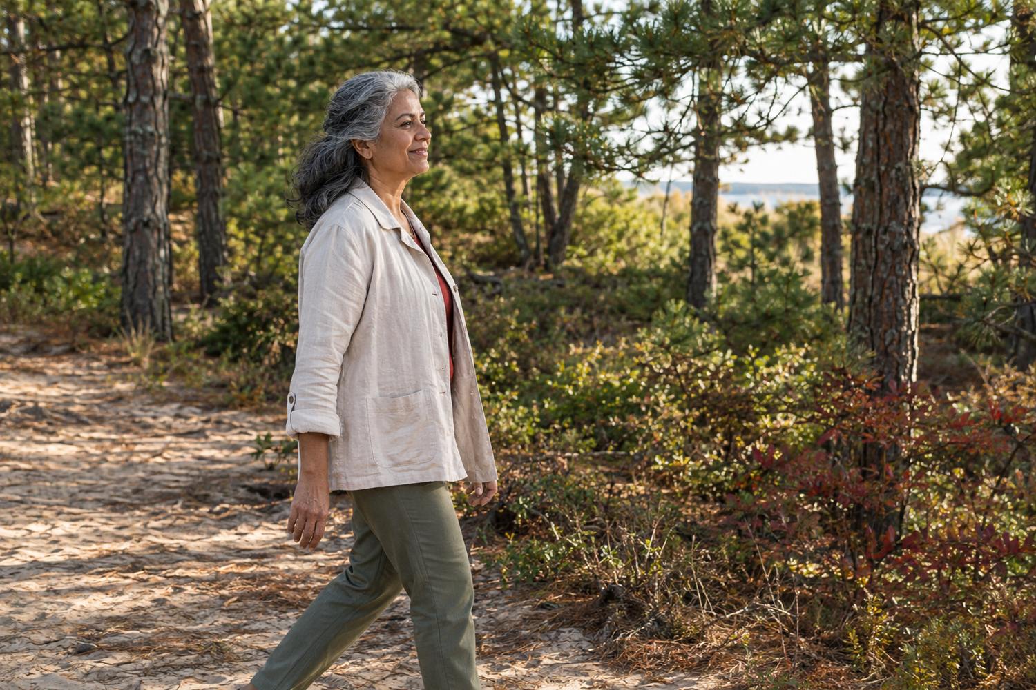 Older woman walking along a sunlit woodland path